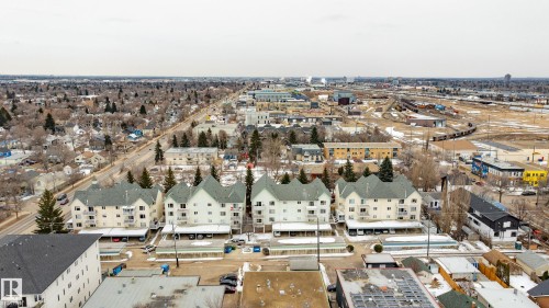 Aerial view showcasing the property's exterior, featuring a light-colored facade, balconies, and covered parking spaces - 25 9926 80 Avenue, Edmonton, AB - Outdoor With View