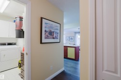 The property features a laundry area with white cabinetry and appliances, visible from a hallway - 