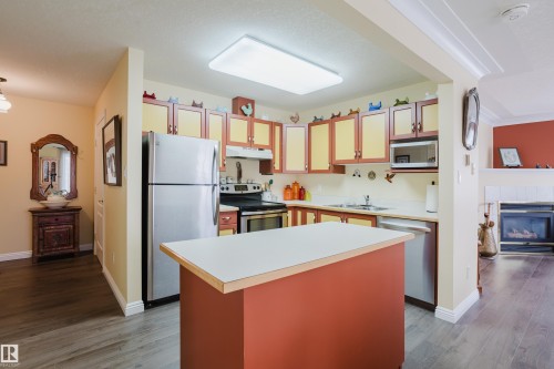 The kitchen features a functional island, stainless steel appliances, and two-toned cabinetry - 25 9926 80 Avenue, Edmonton, AB - Indoor Photo Showing Kitchen