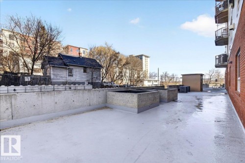 Expansive rooftop area featuring a concrete surface, raised concrete planters, and a red brick exterior wall - 701 9707 105 Street, Edmonton, AB - Outdoor