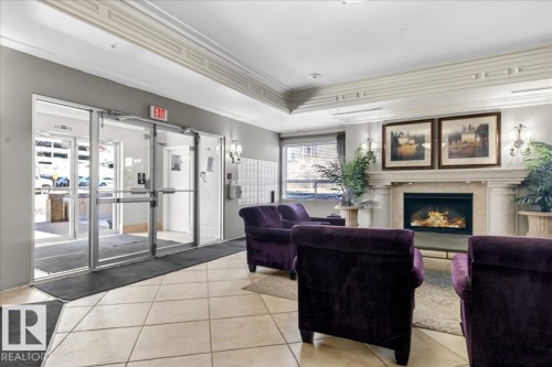 Entryway featuring glass doors, tile flooring, and a decorative fireplace with sconce lighting - 701 9707 105 Street, Edmonton, AB - Indoor With Fireplace