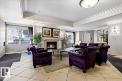 Lobby featuring a fireplace with a stone surround, crown molding, large picture windows, tile flooring, and wall sconces - 