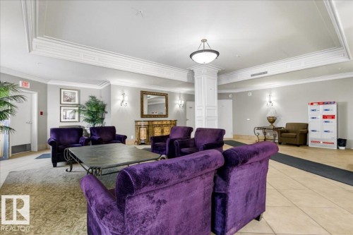 Spacious common area featuring detailed crown molding, a central column with decorative paneling, recessed lighting, and wall-mounted sconces - 701 9707 105 Street, Edmonton, AB - Indoor