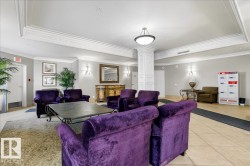Spacious common area featuring detailed crown molding, a central column with decorative paneling, recessed lighting, and wall-mounted sconces - 