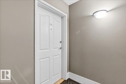Entry door with panel detailing, coordinating trim, and a modern wall-mounted light fixture - 