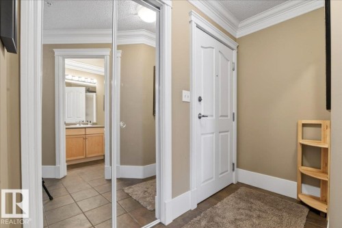 Mirrored closet doors with white trim and crown molding - 701 9707 105 Street, Edmonton, AB - Indoor Photo Showing Other Room