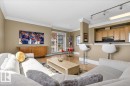 Open-concept living space featuring wood-finish flooring, crown molding, and a kitchen bar with track lighting - 701 9707 105 Street, Edmonton, AB  - Indoor Photo Showing Living Room 