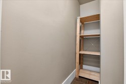 Built-in wood shelving unit featuring four tiers, neutral wall paint, white baseboards, and tile flooring - 