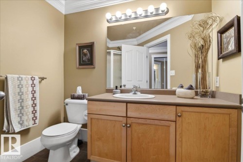 Bathroom featuring a light wood-finish vanity with a single sink, an expansive wall mirror, a five-bulb vanity light fixture, and a toilet - 701 9707 105 Street, Edmonton, AB - Indoor Photo Showing Bathroom