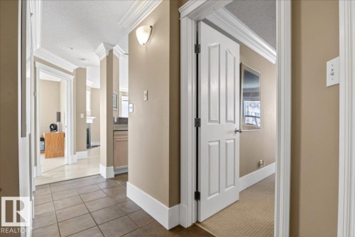 Hallway with tile flooring, crown molding, base molding, and a wall sconce - 701 9707 105 Street, Edmonton, AB - Indoor Photo Showing Other Room