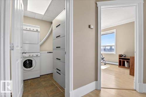 Dedicated laundry area featuring stacked white appliances and tiled flooring - 701 9707 105 Street, Edmonton, AB - Indoor Photo Showing Laundry Room