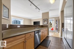 Kitchen featuring light wood cabinetry, stainless steel dishwasher, and a stone-finish countertop with an integrated sink - 