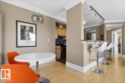 Open-concept living space with blonde wood-finish flooring, a breakfast bar, and crown molding - 