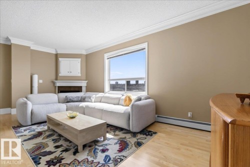 Living area featuring light wood-finish flooring and a corner fireplace with built-in cabinetry - 701 9707 105 Street, Edmonton, AB - Indoor Photo Showing Living Room With Fireplace