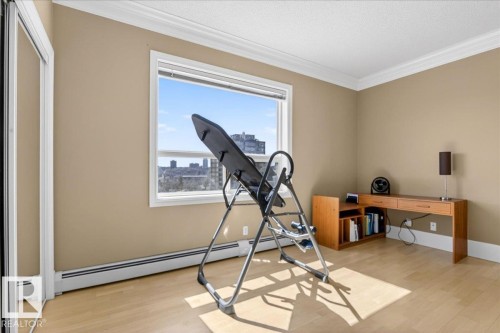 Bright room featuring wood-finish flooring, a large window, and crown molding - 701 9707 105 Street, Edmonton, AB - Indoor