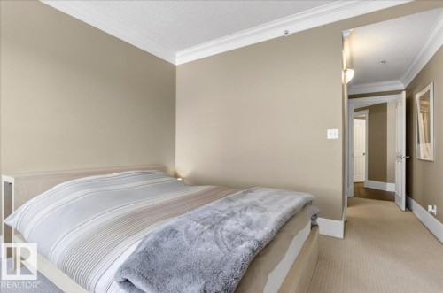 Carpeted bedroom featuring neutral wall tones, crown molding, and white baseboards - 701 9707 105 Street, Edmonton, AB - Indoor Photo Showing Bedroom