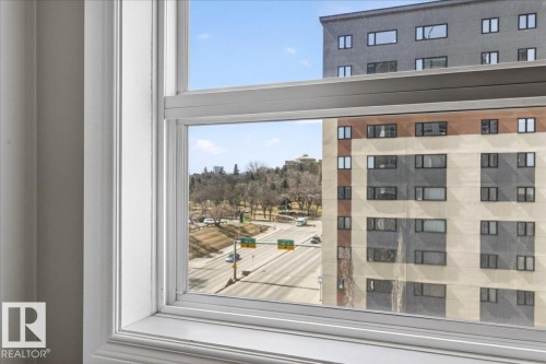 White-framed window offering urban scenery, including a multi-story building and a thoroughfare - 701 9707 105 Street, Edmonton, AB - Indoor Photo Showing Other Room
