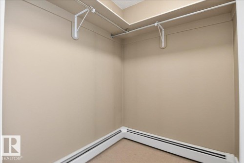 Corner closet featuring neutral-toned walls, overhead shelving, and baseboard heating - 701 9707 105 Street, Edmonton, AB - Indoor With Storage