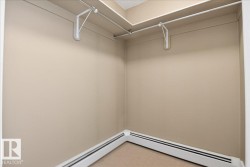 Corner closet featuring neutral-toned walls, overhead shelving, and baseboard heating - 