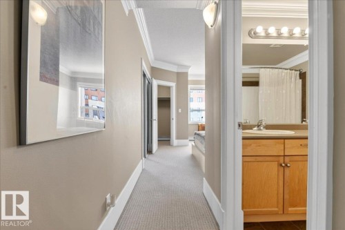 Hallway featuring carpet flooring, crown molding, and a wall sconce - 701 9707 105 Street, Edmonton, AB - Indoor Photo Showing Other Room