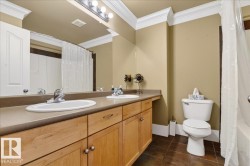 Double vanity with dual basins, light wood-finish cabinetry, and neutral countertops - 