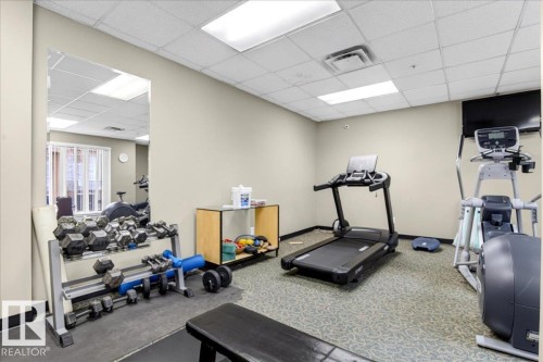 Dedicated fitness room featuring carpet flooring with a patterned design, a mirrored wall, and recessed ceiling lighting - 701 9707 105 Street, Edmonton, AB - Indoor Photo Showing Gym Room