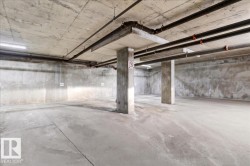 Spacious subterranean parking area featuring concrete flooring, exposed concrete walls, and concrete support pillars - 