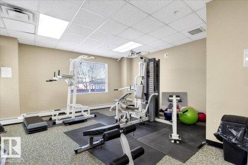 Fitness room featuring a multi-station gym, weight bench, exercise steps, and soft carpet flooring - 701 9707 105 Street, Edmonton, AB - Indoor Photo Showing Gym Room