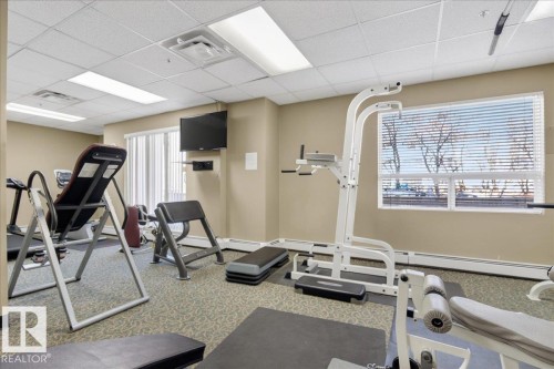Dedicated fitness room featuring patterned carpeting and a window with blinds - 701 9707 105 Street, Edmonton, AB - Indoor Photo Showing Gym Room