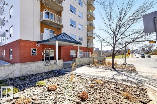 Multi-story building featuring a brick base, white facade, and multiple private balconies with white railings - 701 9707 105 Street, Edmonton, AB - Outdoor With Balcony