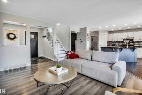 Open-concept living space featuring wood-finish flooring, recessed lighting, and a kitchen with white cabinetry - 96 Bonin Crescent, Beaumont, AB - Indoor Photo Showing Living Room