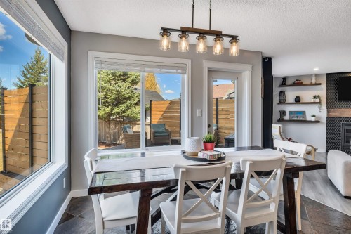 Dining area featuring a linear chandelier with glass shades, slate tile flooring, and a large picture window - 96 Bonin Crescent, Beaumont, AB - Indoor Photo Showing Dining Room