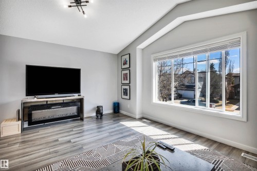 Living area featuring large multi-pane windows, vaulted ceilings, and wood-finish flooring - 96 Bonin Crescent, Beaumont, AB - Indoor Photo Showing Living Room