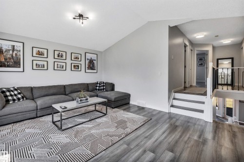 Living area featuring wood-finish flooring, vaulted ceiling, and a contemporary ceiling light fixture - 96 Bonin Crescent, Beaumont, AB - Indoor Photo Showing Living Room