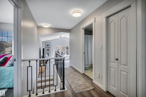 Hallway featuring wood-finish flooring, contemporary flush mount lighting, and white bi-fold closet doors - 96 Bonin Crescent, Beaumont, AB - Indoor Photo Showing Other Room