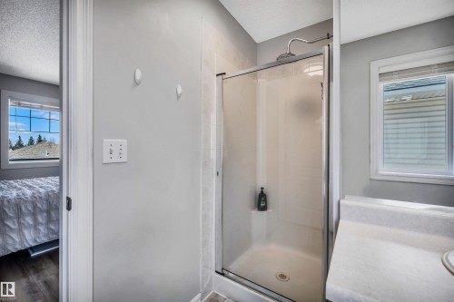 Three-piece bathroom with a glass-enclosed shower, built-in vanity with integrated sink, and light gray wall paint - 96 Bonin Crescent, Beaumont, AB - Indoor Photo Showing Bathroom