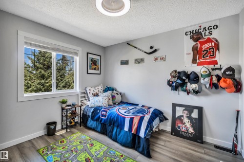 Bedroom featuring wood-finish flooring, a white trim window, and neutral wall paint - 96 Bonin Crescent, Beaumont, AB - Indoor Photo Showing Bedroom
