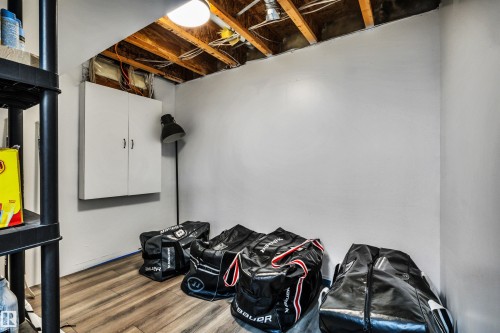Finished lower level space featuring wood-finish flooring, white painted walls, exposed ceiling joists, and a built-in wall cabinet - 96 Bonin Crescent, Beaumont, AB - Indoor Photo Showing Basement