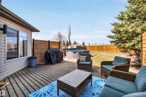 Expansive backyard featuring a wood-finish deck, privacy fencing, and mature trees - 96 Bonin Crescent, Beaumont, AB - Outdoor With Deck Patio Veranda With Exterior