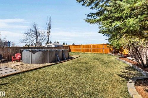 Expansive backyard featuring a manicured lawn, full privacy fencing, and mature trees - 96 Bonin Crescent, Beaumont, AB - Outdoor