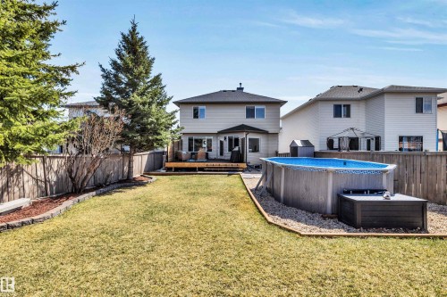 Expansive backyard featuring a manicured lawn, a raised wooden deck, and an above-ground pool with surrounding gravel - 96 Bonin Crescent, Beaumont, AB - Outdoor With Above Ground Pool With Backyard With Exterior