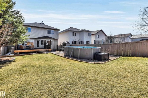 Expansive backyard featuring a manicured lawn, a raised wood deck, a privacy fence, an above-ground pool, and a gravel-bordered pool area - 96 Bonin Crescent, Beaumont, AB - Outdoor With Above Ground Pool With Backyard With Exterior