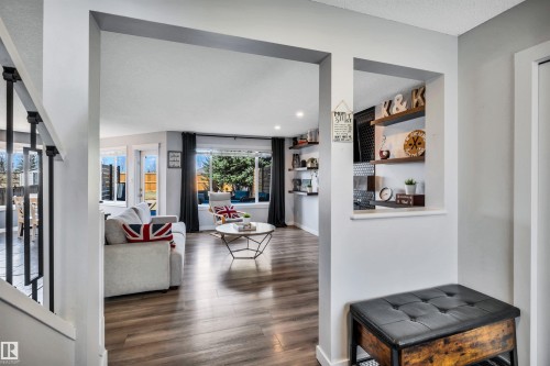 Open-concept living area featuring wood-finish flooring, recessed lighting, and large windows with dark drapery - 96 Bonin Crescent, Beaumont, AB - Indoor
