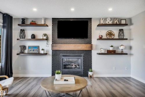 Floor-to-ceiling fireplace with black hexagonal tile surround, wood mantel, and integrated firebox - 96 Bonin Crescent, Beaumont, AB - Indoor Photo Showing Living Room With Fireplace
