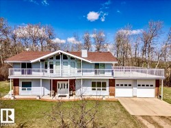 Split-level residence featuring a prominent balcony, a two-car garage, and a peaked roofline - 