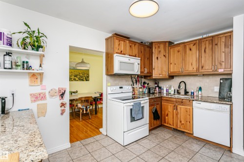 Kitchen featuring wood-finish cabinetry, granite-style countertops, and a tile backsplash - 9760 64 Avenue, Edmonton, AB - Indoor Photo Showing Kitchen
