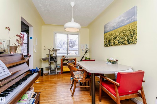 Dining area featuring wood-finish flooring, a contemporary pendant light fixture, and a large window - 9760 64 Avenue, Edmonton, AB - Indoor Photo Showing Dining Room
