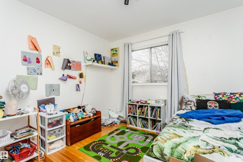 Room featuring wood-finish flooring, a window with grey curtains, and white walls - 9760 64 Avenue, Edmonton, AB - Indoor Photo Showing Bedroom