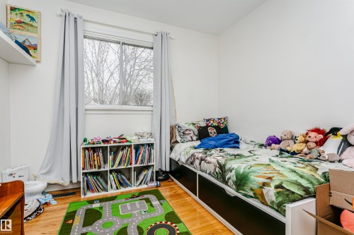 Bright room featuring wood-finish flooring and a large window with white trim - 9760 64 Avenue, Edmonton, AB - Indoor Photo Showing Bedroom