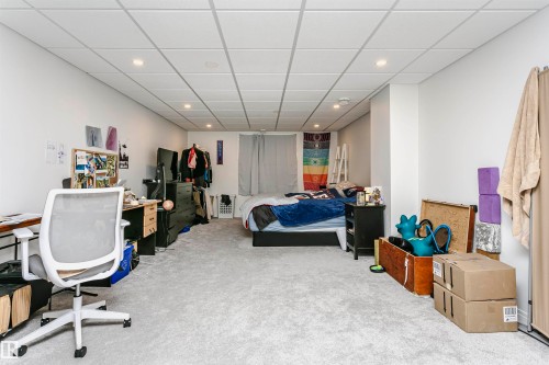 Carpeted room with recessed lighting and a drop ceiling, featuring white walls and a structural column - 9760 64 Avenue, Edmonton, AB - Indoor